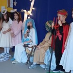 dzieci siedzą na scenie w strojach