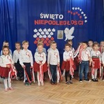 dzieci w strojach biało czerwonych stoją ze wstążkami
