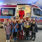 dzieci z ratownikiem medycznym stoją przed ambulansem