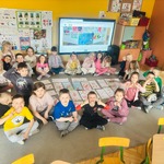 dzieci siedzą na dywanie  z własnoręcznie zrobionymi  plakatami 