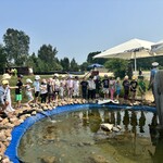 dzieci stoją w grupie przy oczku wodnym