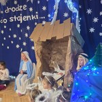 dzieci- aktorzy siedzą przy szopce.jpg