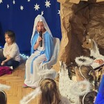 dziewczynka w przebraniu Maryi przy żłóbku.jpg