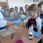 dzieci z pomocą nauczyciela wykonują doświadczenie chemiczne.jpg