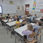 dzieci siedzą w szkolnych ławkach.jpg