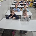 dzieci siedzą w ławkach  w sali lekcyjnej.jpg