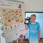 chłopiec z pacynką kotka stoi obok tablicy z planszą z białostockimi misiami.jpg